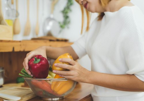 Asian woman making healthy food standing happy smiling in kitchen preparing salad. Beautiful cheerful Asian young woman at home. Healthy food dieting and healthy lifestyle cooking at home Concept.