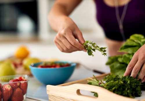 Close-up of woman using parsley while making healthy food in the kitchen.