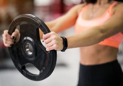 Woman at gym exercising with weight plate